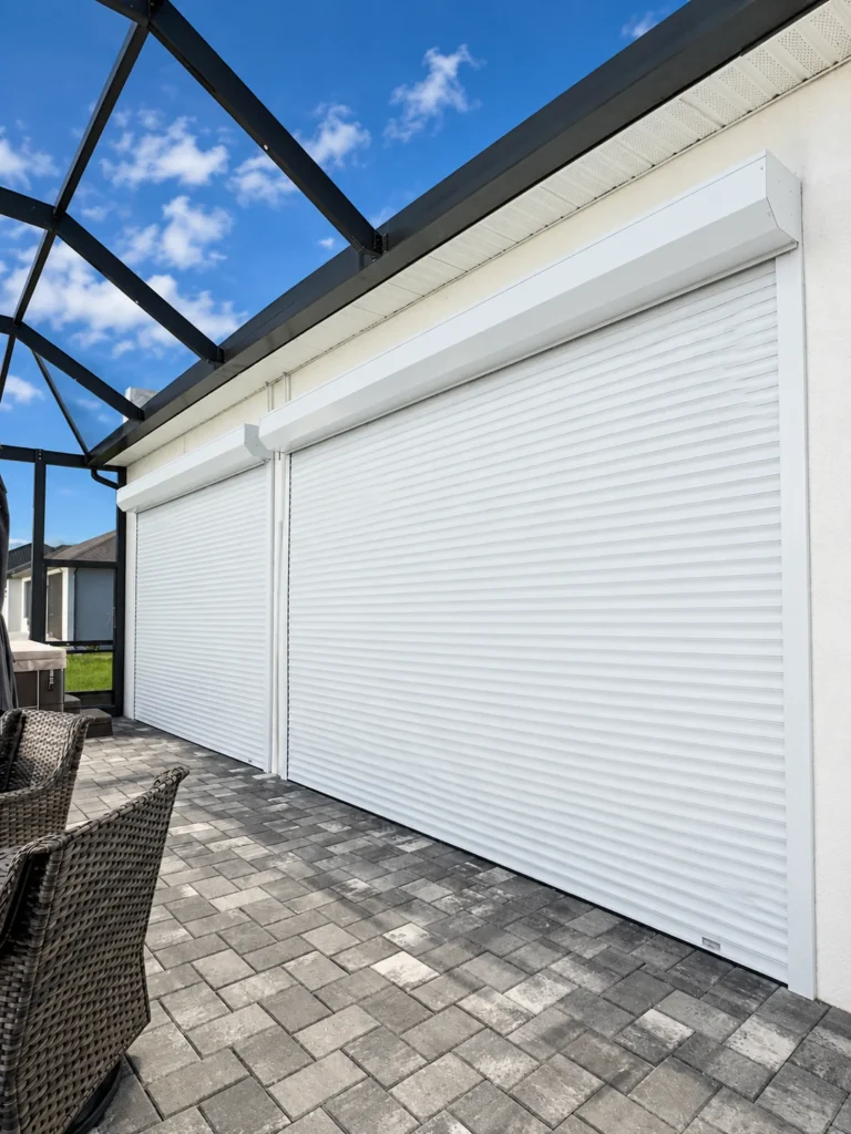 Two closed white roll-down shutters beside a screened patio